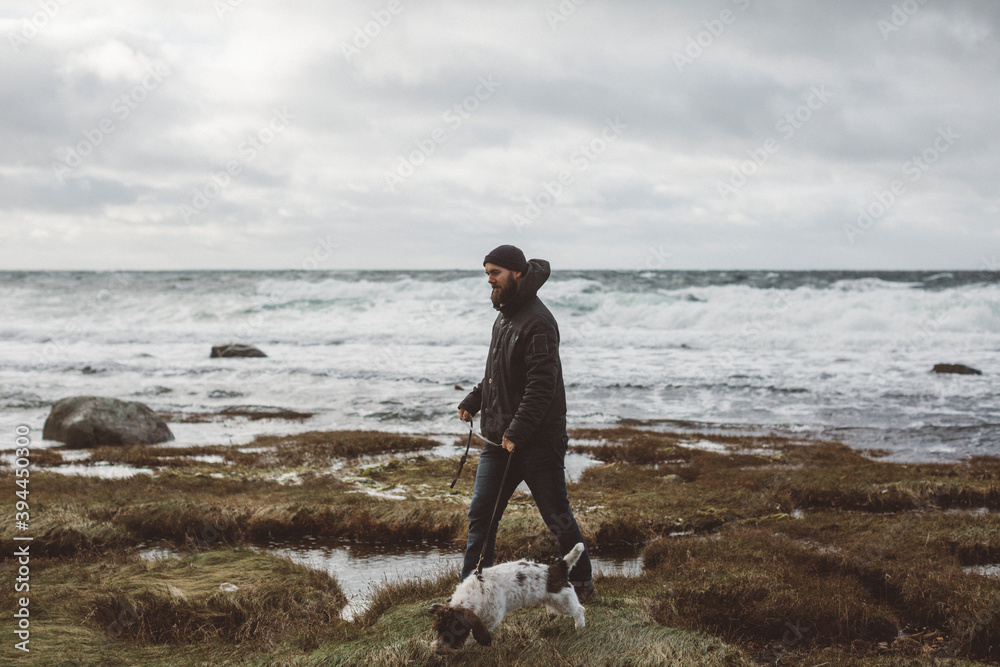 Man walking with dog along coast, Sweden Man walking with dog along coast, Sweden
