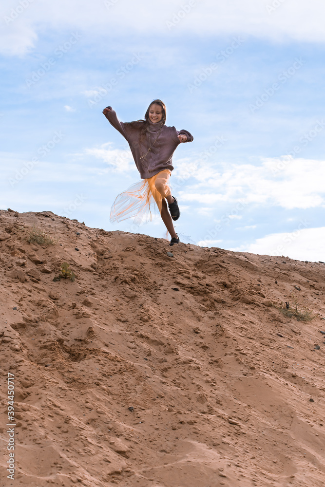 Preteen girl running from sand hill, smiling and enjoying Preteen girl running from sand hill, smiling and enjoying
