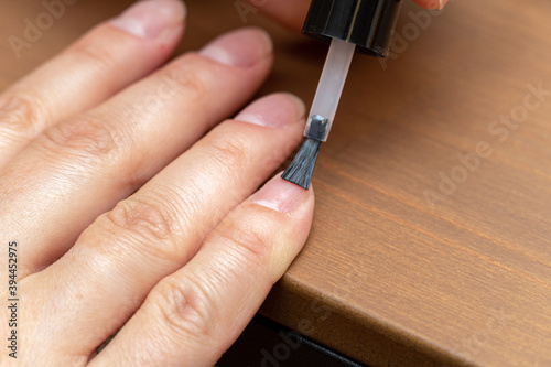 Applying primer, colorless nail polish with brush on finger