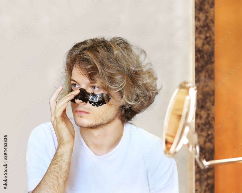 Fototapeta premium cleansing mask,facial mask, acne and oily skin. young man taking care of his face . man moisturizing face mask. Cosmetology and skin care concept.