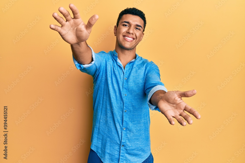 Young arab man wearing casual clothes looking at the camera smiling with open arms for hug. cheerful expression embracing happiness. Young arab man wearing casual clothes looking at the camera smiling with open arms for hug. cheerful expression embracing happiness.