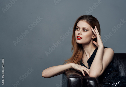 Foto Woman in black dress gestures with her hands on gray background Copy Space