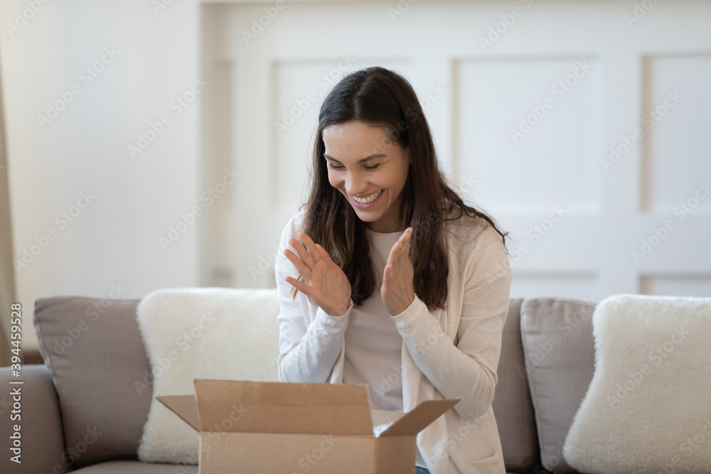 What a cute thing. Excited overjoyed young woman shopper unboxing parcel shipped by mail feeling happy satisfied by quick reliable courier service, high quality of goods products ordered by internet What a cute thing. Excited overjoyed young woman shopper unboxing parcel shipped by mail feeling happy satisfied by quick reliable courier service, high quality of goods products ordered by internet