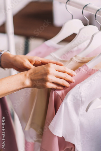 Season of discounts in the store, women's hands and casual clothes on hangers close up