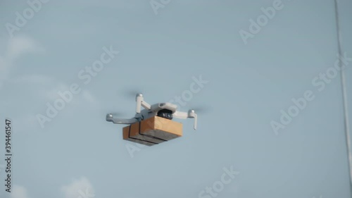 flying on a sky delivery drone with holding a .cardboard parcel photo