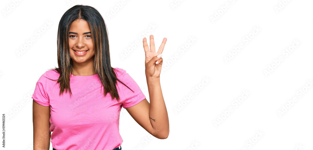 Young latin girl wearing casual clothes showing and pointing up with fingers number three while smiling confident and happy.