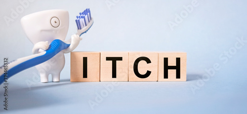 The inscription ITCH on wooden cubes on a light blue background together with pedmets related to stomatology. Health and medicine concept. photo