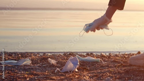 Volunteer collecting used face masks trash at the beach. Environmental problem after coronavirus pandemic photo