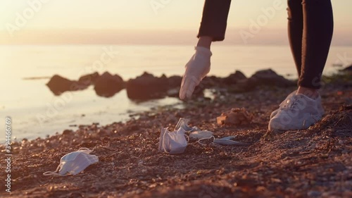 Volunteer collecting used face masks trash at the beach. Environmental problem after coronavirus pandemic photo