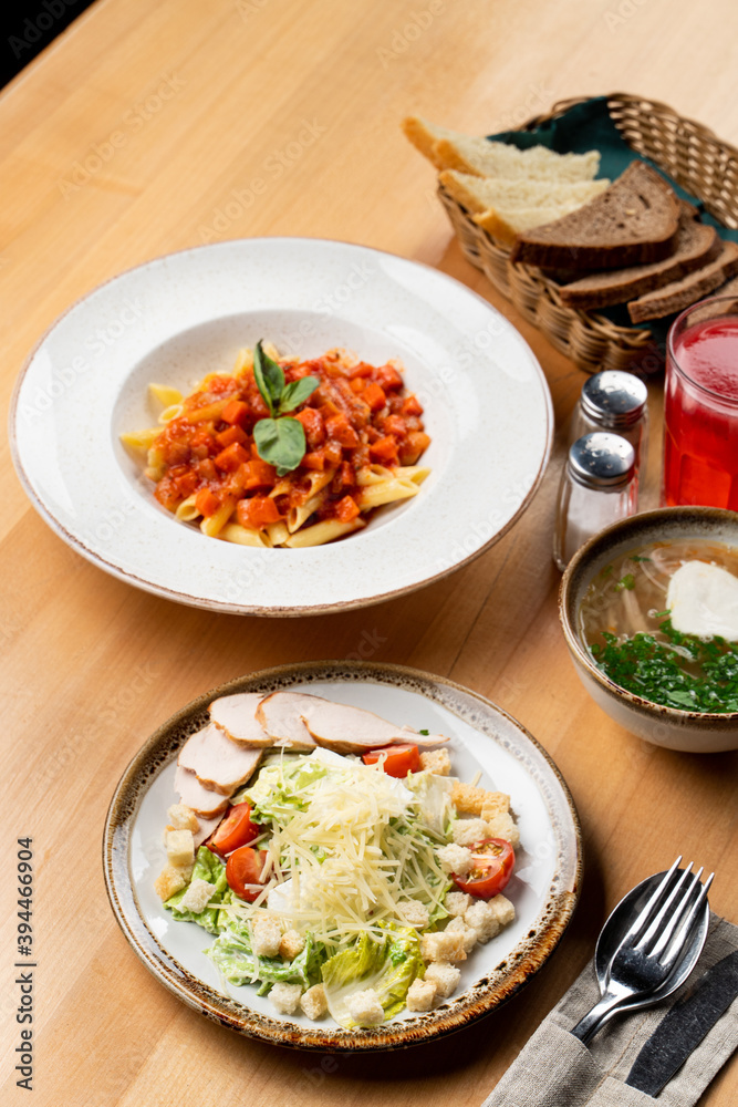 Business lunch in a italian cafe: caesar salad, chicken soup and tomato penne pasta, menu photography Business lunch in a italian cafe: caesar salad, chicken soup and tomato penne pasta, menu photography