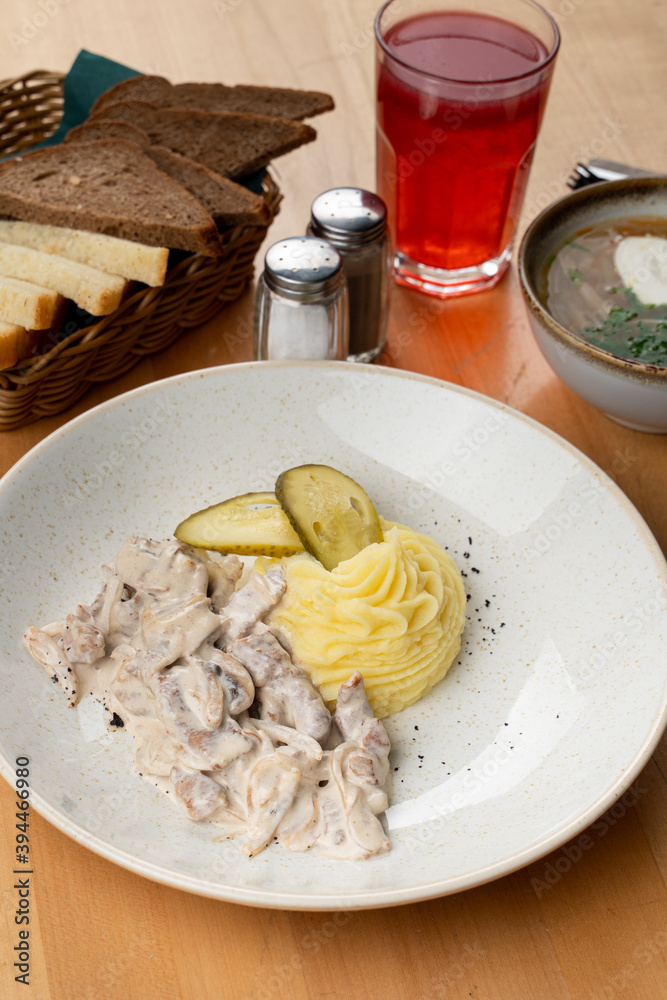 Beef stroganoff with champignons and creamy sauce, served with mashed potato and pickles