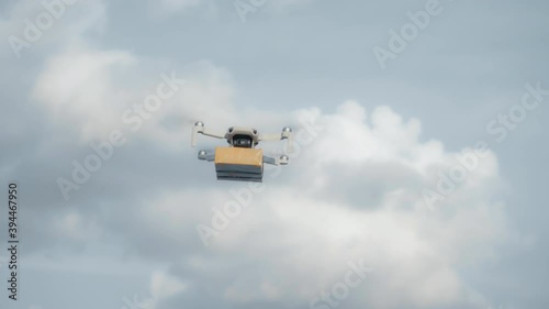 flying on a sky delivery drone with holding a .cardboard parcel photo