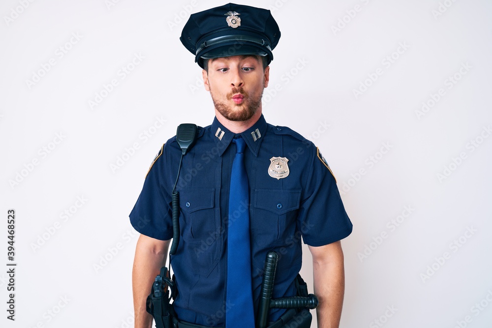 Young caucasian man wearing police uniform making fish face with lips, crazy and comical gesture. funny expression. Young caucasian man wearing police uniform making fish face with lips, crazy and comical gesture. funny expression.