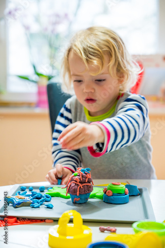 Cute girl playing with many colorful doughs.