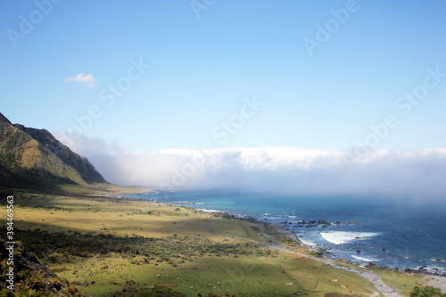 glorious green coast with mountains on the left and clouds flowing across the sea over the horizon