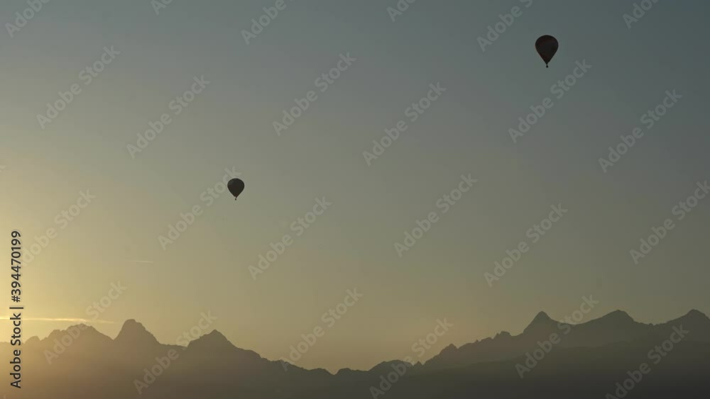 Two balloons fly along the mountains. Mountains and balloons in silhouette. General plan. Morning. The sun's rays illuminate the silhouettes of mountains Two balloons fly along the mountains. Mountains and balloons in silhouette. General plan. Morning. The sun's rays illuminate the silhouettes of mountains