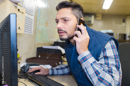 supervisor using cell phone and pc at warehouse photo