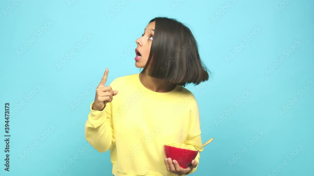 Young latin woman eating a cereals bowl pointing upside with opened mouth Young latin woman eating a cereals bowl pointing upside with opened mouth