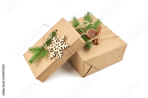 Two christmas gift boxes decorated with fir tree branch and wooden snowflakes isolated on white background © nikavera
