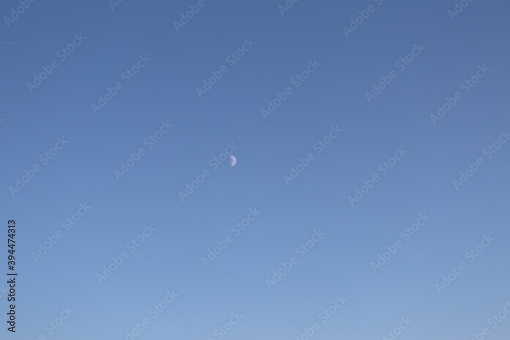 Vue de la lune dans le ciel bleu en journée, ville de Corbas, département du Rhône, France Vue de la lune dans le ciel bleu en journée, ville de Corbas, département du Rhône, France