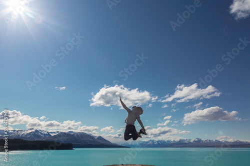 Holiday time! Funny silhouette of young man jumping from the beach by the Tekapo Lake, New Zealand. Concept about lifestyle, travel, nature and people. © MayR