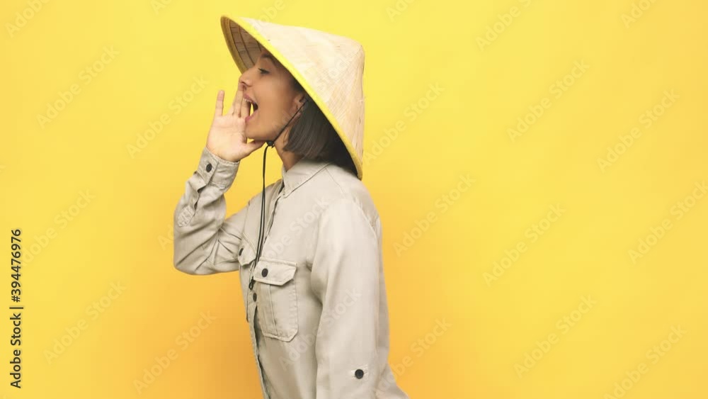 Young latin woman with vietnamite hat shouting and holding palm near opened mouth Young latin woman with vietnamite hat shouting and holding palm near opened mouth