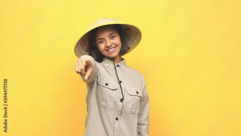 Young latin woman with vietnamite hat laughing pointing forward Young latin woman with vietnamite hat laughing pointing forward
