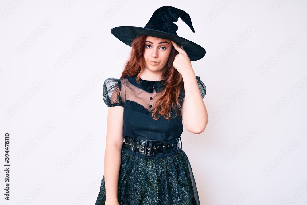 Young beautiful woman wearing witch halloween costume pointing unhappy to pimple on forehead, ugly infection of blackhead. acne and skin problem Young beautiful woman wearing witch halloween costume pointing unhappy to pimple on forehead, ugly infection of blackhead. acne and skin problem