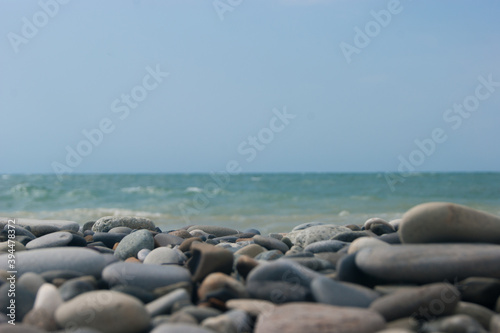 Beach. View of the sea and smooth horizon from the pebble beach. In the foreground are large pebble stones. It's a focus. Background for blog or site, photowallpaper for computer.