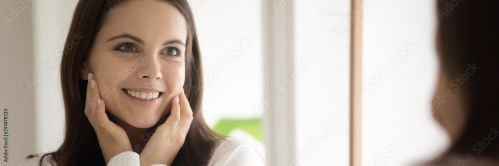 Getting velvet cheeks. Wide banner image of mirror reflection of happy satisfied millennial woman client customer of beauty salon shop enjoying touching her smooth silky face skin after spa procedures Getting velvet cheeks. Wide banner image of mirror reflection of happy satisfied millennial woman client customer of beauty salon shop enjoying touching her smooth silky face skin after spa procedures