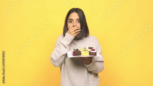 Young latin woman holding muffins surprised and shocked