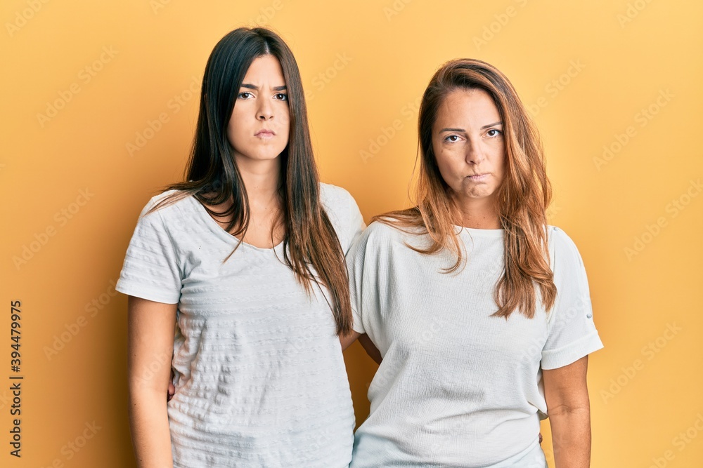 Hispanic family of mother and daughter wearing casual white tshirt skeptic and nervous, frowning upset because of problem. negative person. Hispanic family of mother and daughter wearing casual white tshirt skeptic and nervous, frowning upset because of problem. negative person.