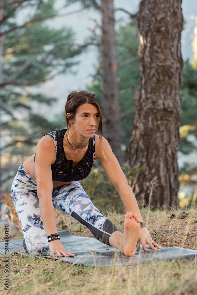 Naklejka premium Woman practices yoga alone in the forest Back view Outdoor activity Young attractive Asian woman practicing yoga, exercising exercising working out Women is meditating alone at sunrise.