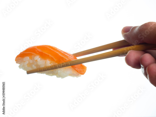 Sushi isolated on white background. Sushi nigiri with salmon in chopsticks. Holding the chopsticks in hand. Japanese food.