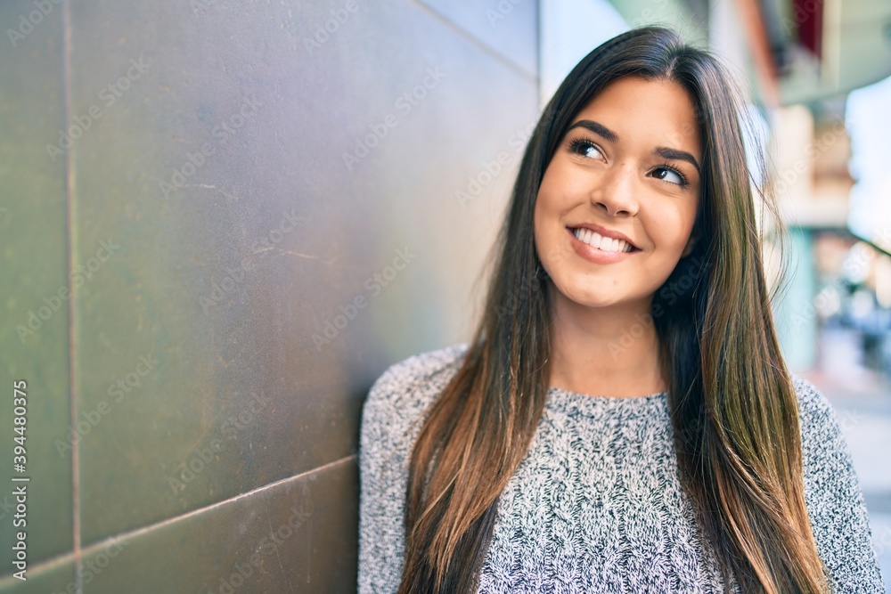 Fototapeta premium Young beautiful hispanic girl smiling happy leaning on the wall at the city.