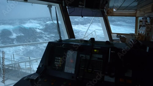View from the bridge of the ship on the big waves. The ship is rocking hard. Storm at sea. A strong wind rips the foam from the crest of the wave. View from the window of the ship's chart room.