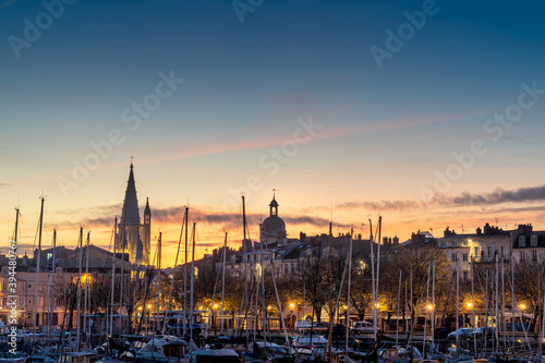 View of the old harbor of La Rochelle at blue hour with church, clock and matt boats