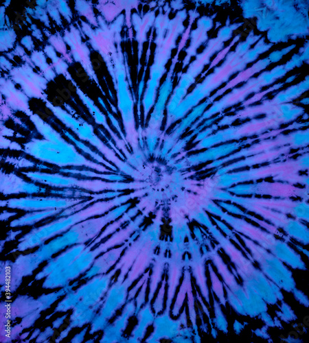 Spiral tie dye texture. Reverse swirl tiedye pattern. Tie-dye background in blue purple.