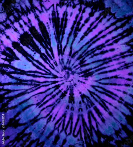 Reverse spiral tie dye in purple blue. Hippie tie-dye pattern texture background wallpaper.