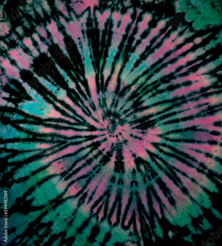 Reverse spiral tie dye in green pink. Hippie tie-dye pattern texture background wallpaper.