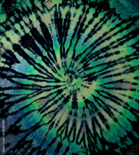 Spiral tie dye texture. Hippie tie-dye wallpaper. Boho festival tiedye background in green.