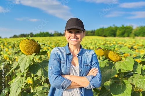 Portrait of woman farmer, agronomist in field with ripe sunflower