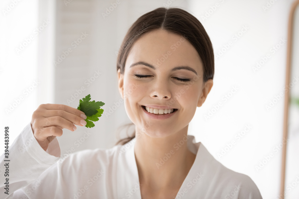 What a nice smell. Young woman with white smile standing with closed eyes rubbing parsley in fingers enjoying fresh aroma proposing to use natural greenery cosmetic products in skin dental daily care What a nice smell. Young woman with white smile standing with closed eyes rubbing parsley in fingers enjoying fresh aroma proposing to use natural greenery cosmetic products in skin dental daily care