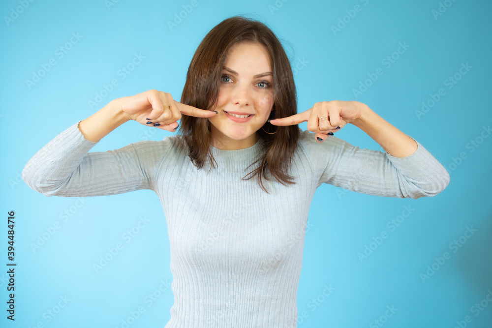 picture of beautiful young woman pointing to teeth over blue background. picture of beautiful young woman pointing to teeth over blue background.