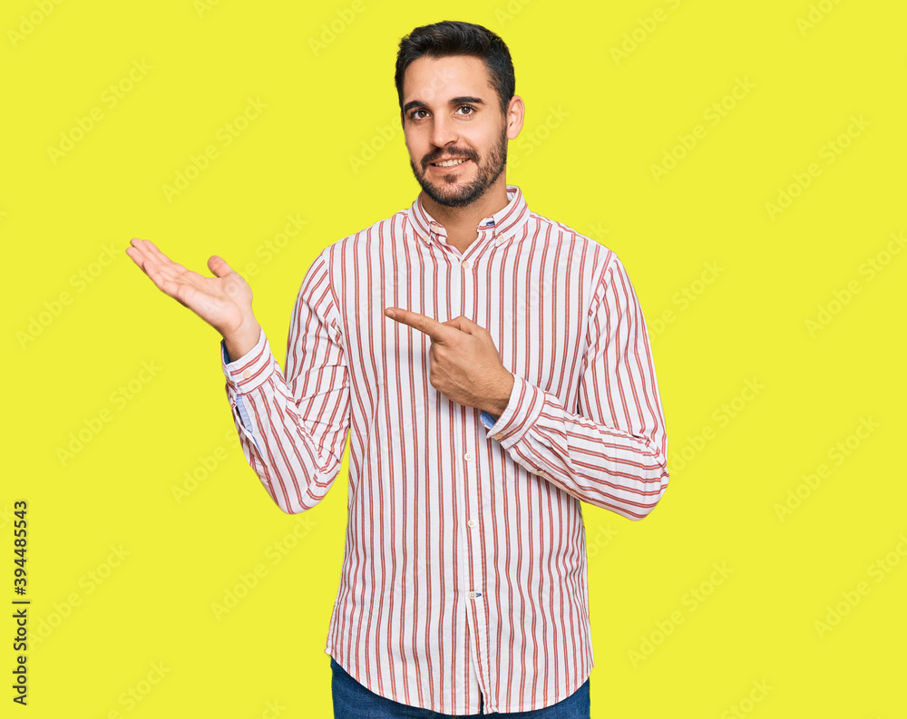 Young hispanic man wearing business shirt amazed and smiling to the camera while presenting with hand and pointing with finger. Young hispanic man wearing business shirt amazed and smiling to the camera while presenting with hand and pointing with finger.