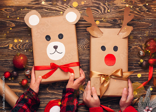 Children hold creatively wrapped Christmas gifts in the shape of a teddy bear and a deer. New Year and Christmas concept. DIY gift wrapping