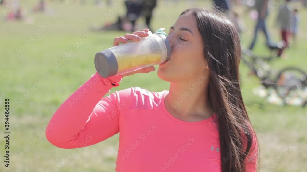 Chica de pelo largo toma jugo en el parque  