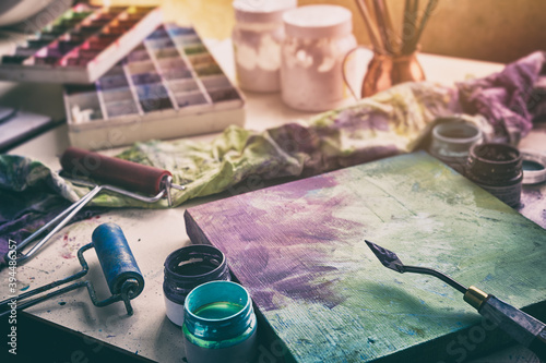 Artistic equipment: canvas and palette knife, paint brushes, multicolored paints in artist studio.