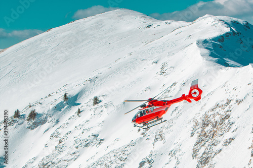 Red helicopter flying in the snowy mountains 