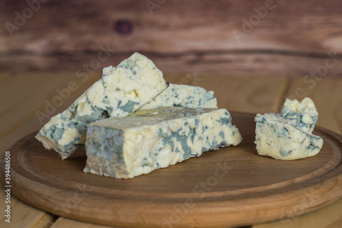 Pieces of blue cheese on a wooden board. Dorblu cheese on a wooden table. photo